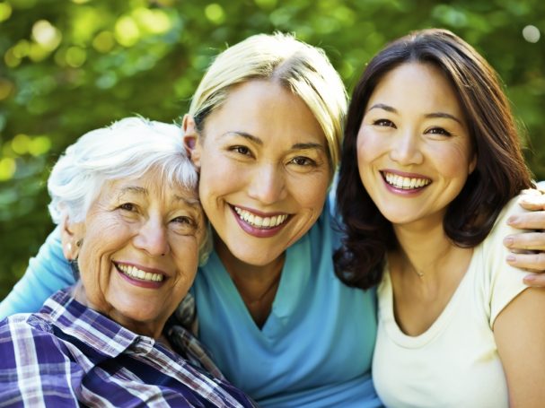 Drei Frauen lächeln freundlich, umgeben von grünem Hintergrund.